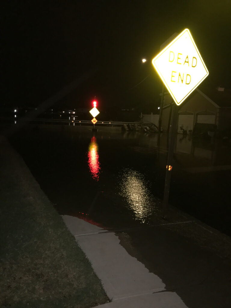 a street sign on a wet street at night (MyCoast AI)