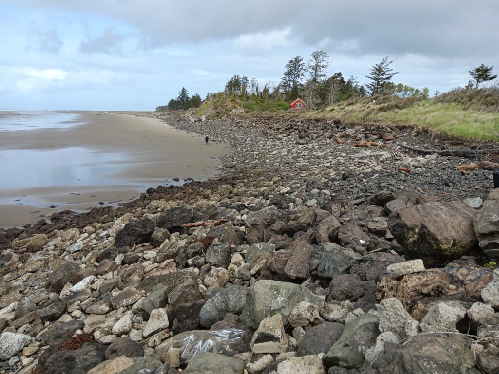 a rocky beach with a house in the background (MyCoast AI)