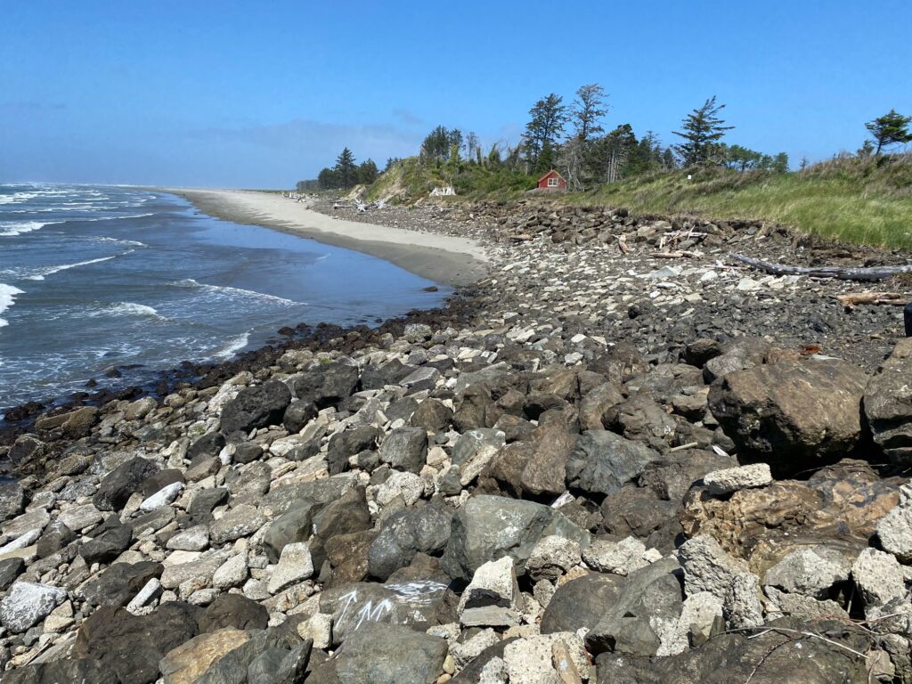 a rocky beach with a house in the background (MyCoast AI)