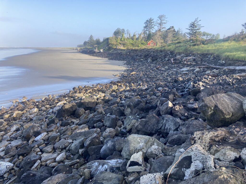 a rocky beach with a house in the background (MyCoast AI)