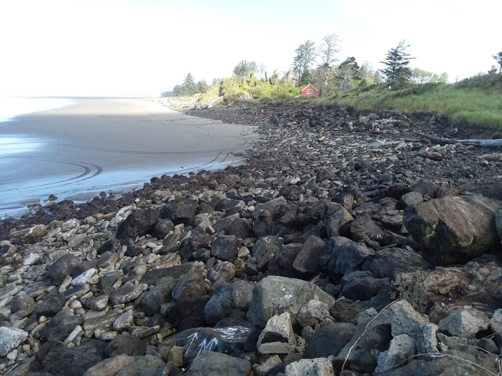 a rocky beach with a red house in the background (MyCoast AI)