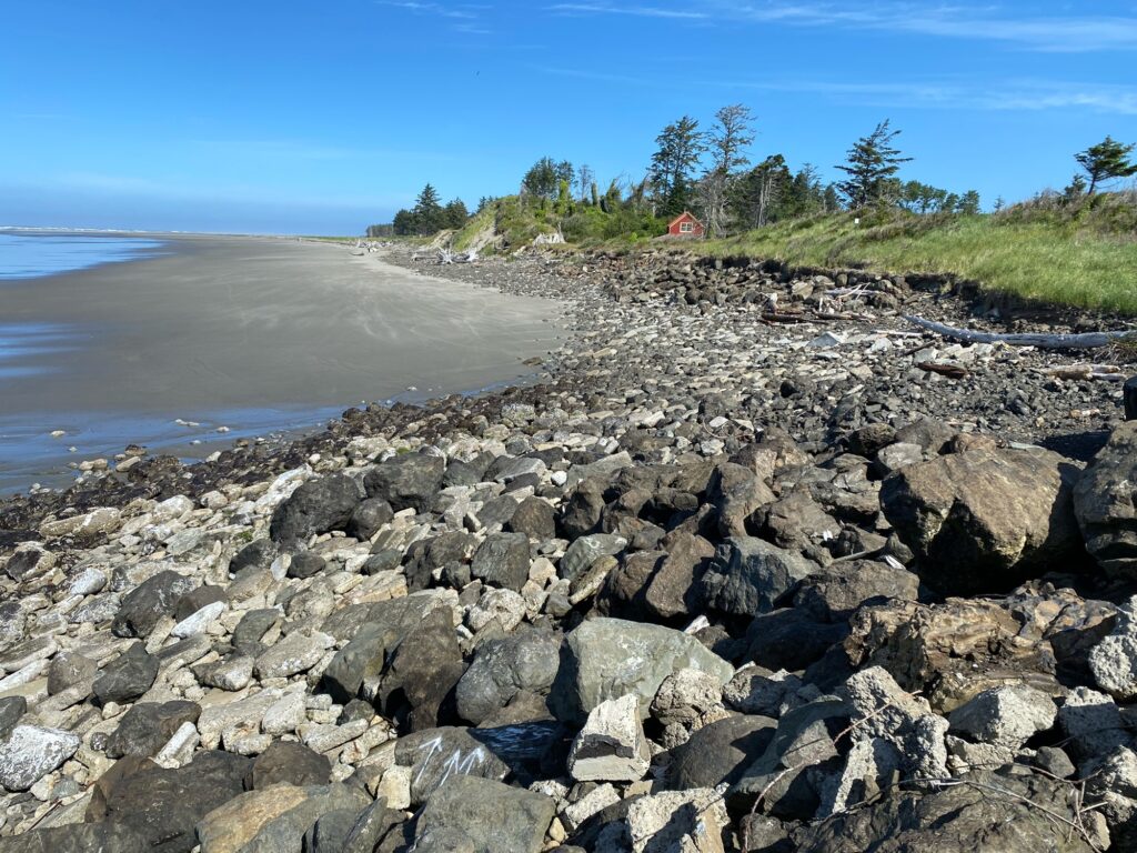 a rocky beach with a house in the background (MyCoast AI)