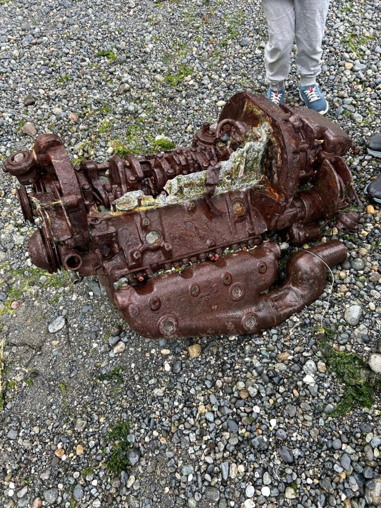 a rusted out metal object on gravel (MyCoast AI)