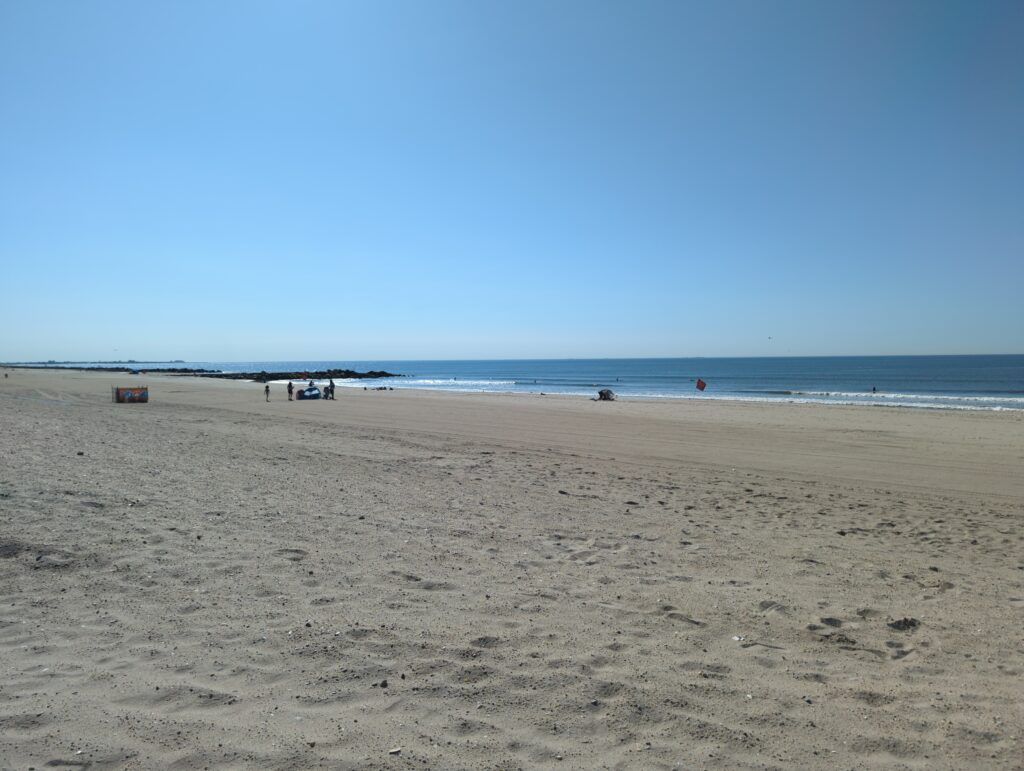 a sandy beach with people and a body of water in the background (MyCoast AI)