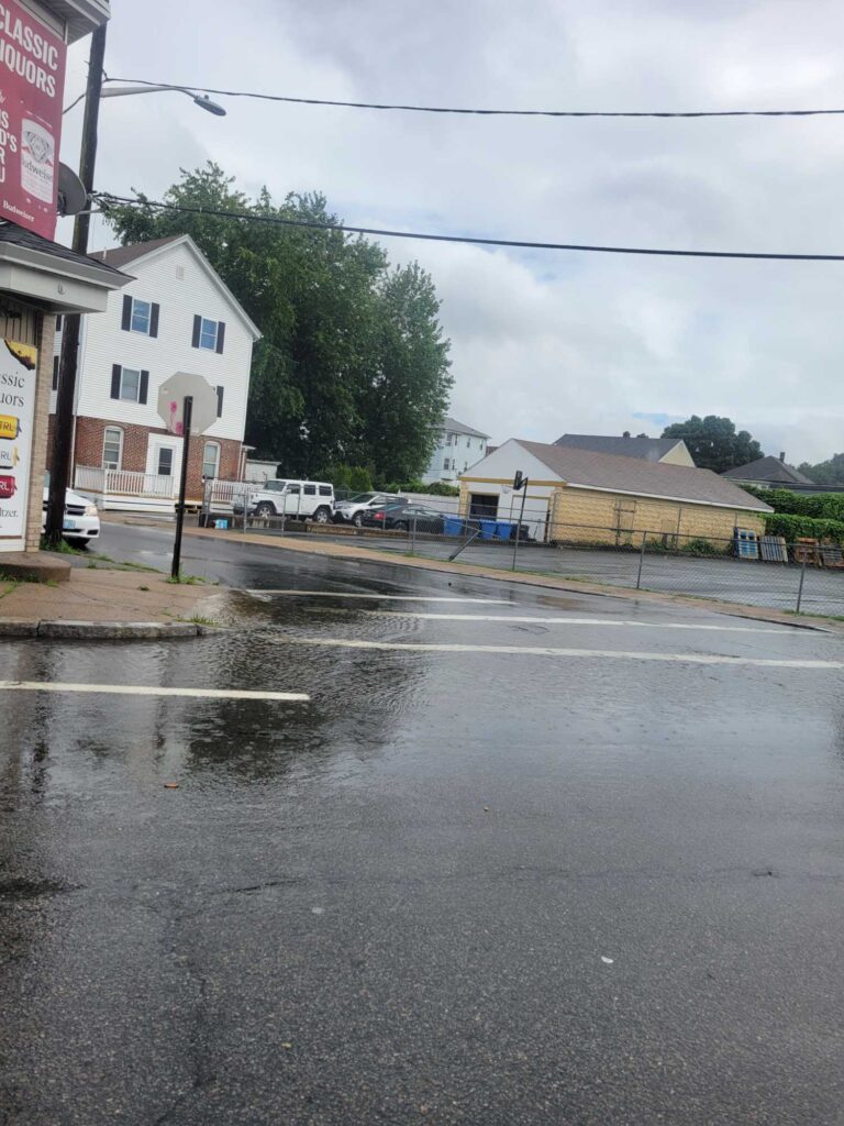 a wet street with buildings and cars (MyCoast AI)