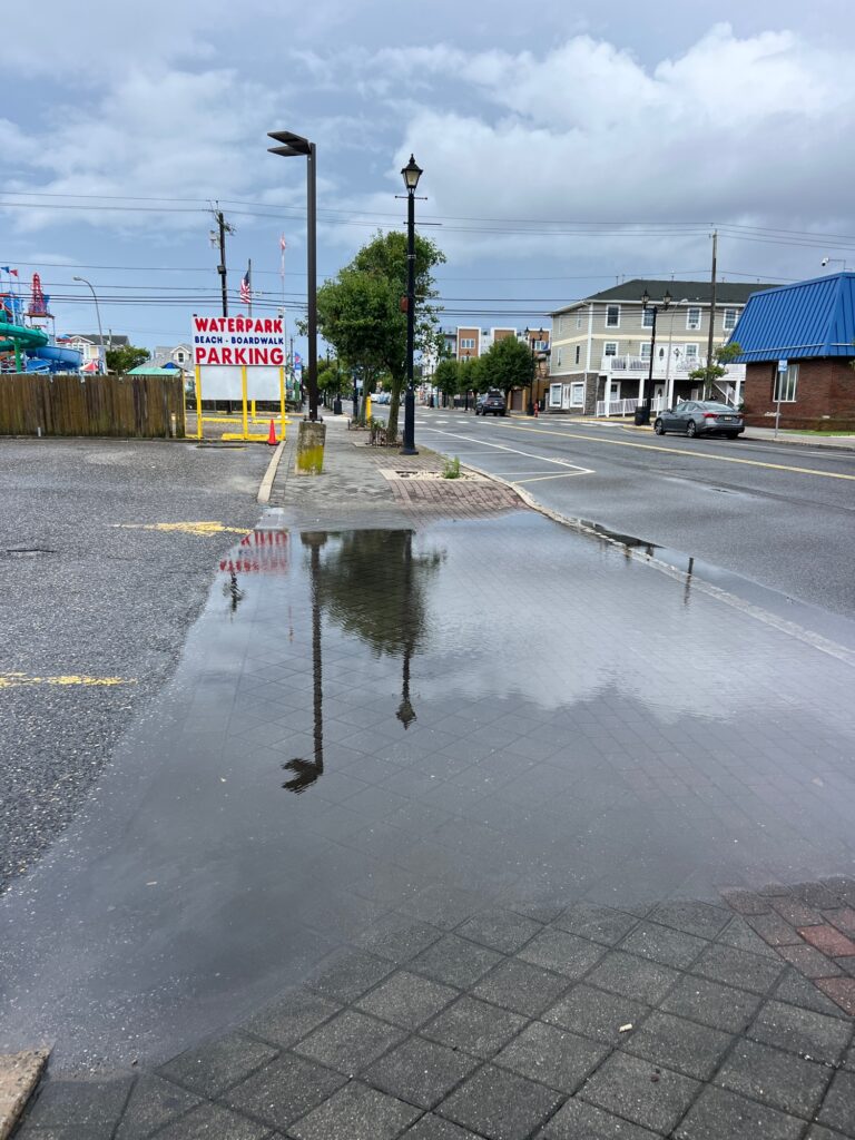 a wet street with a puddle of water on the ground (MyCoast AI)