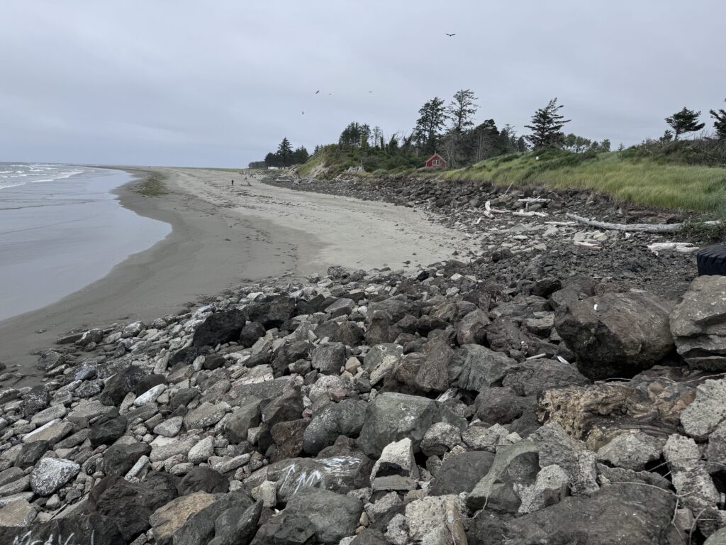 a rocky beach with a house in the distance (MyCoast AI)