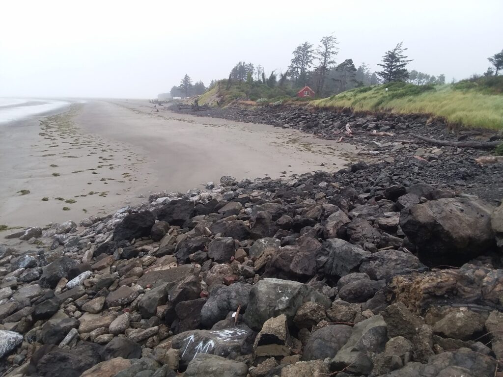 a rocky beach with a house in the background (MyCoast AI)