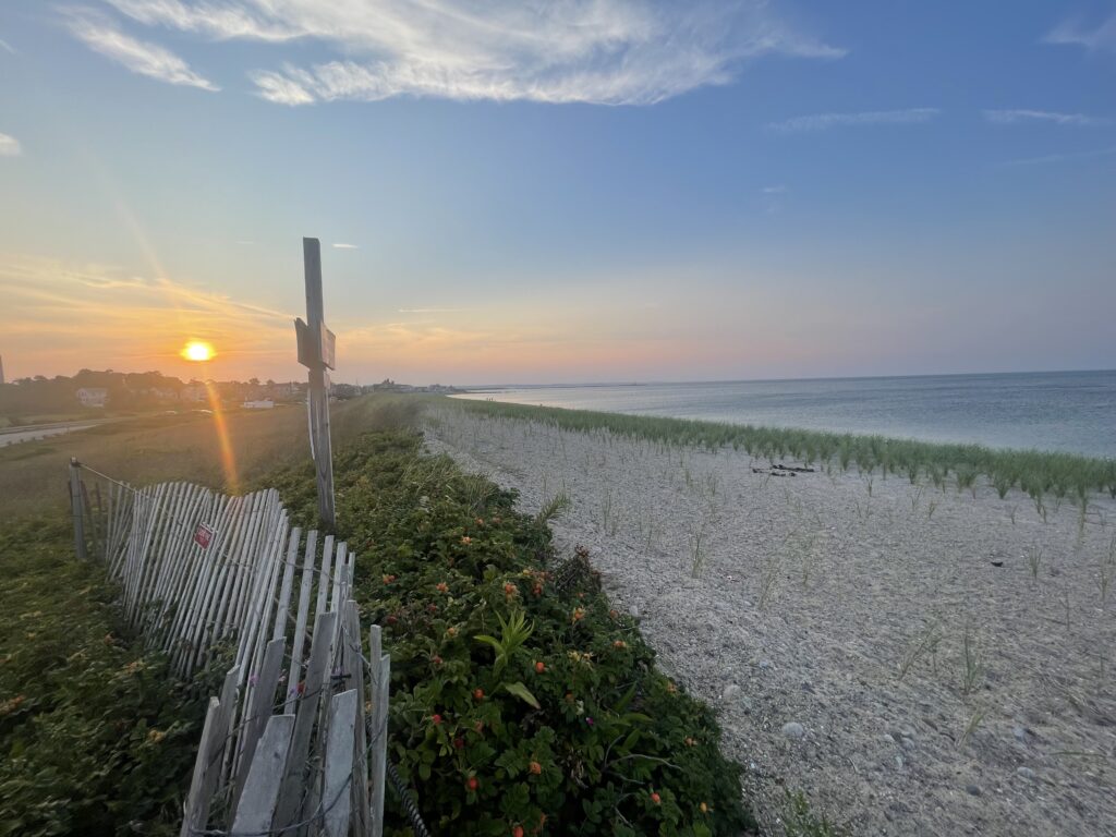 a beach with a fence and a sunset (MyCoast AI)