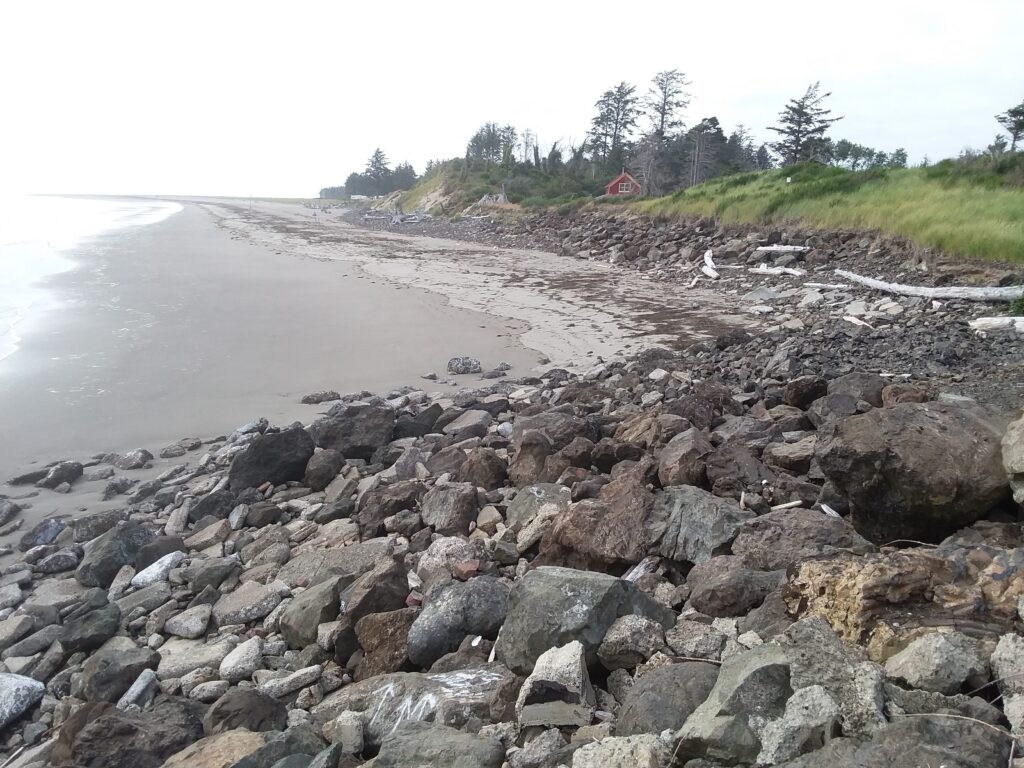 a rocky beach with a house in the background (MyCoast AI)