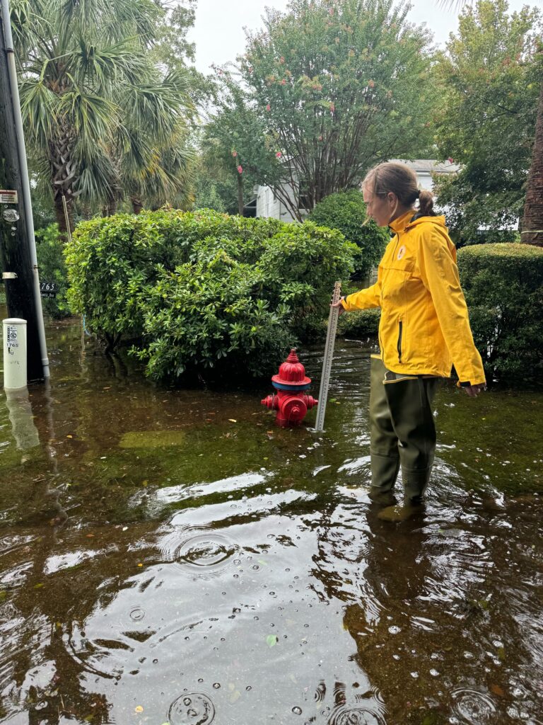 a person in a yellow raincoat holding a red fire hydrant (MyCoast AI)