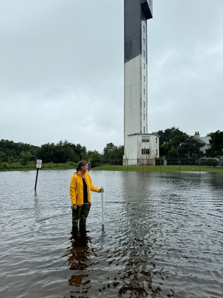 a man standing in a body of water with a tall tower in the background (MyCoast AI)