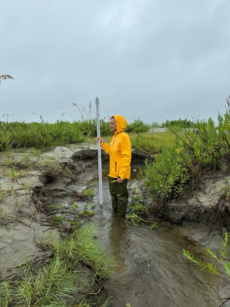 a man in a yellow raincoat standing in a muddy area (MyCoast AI)