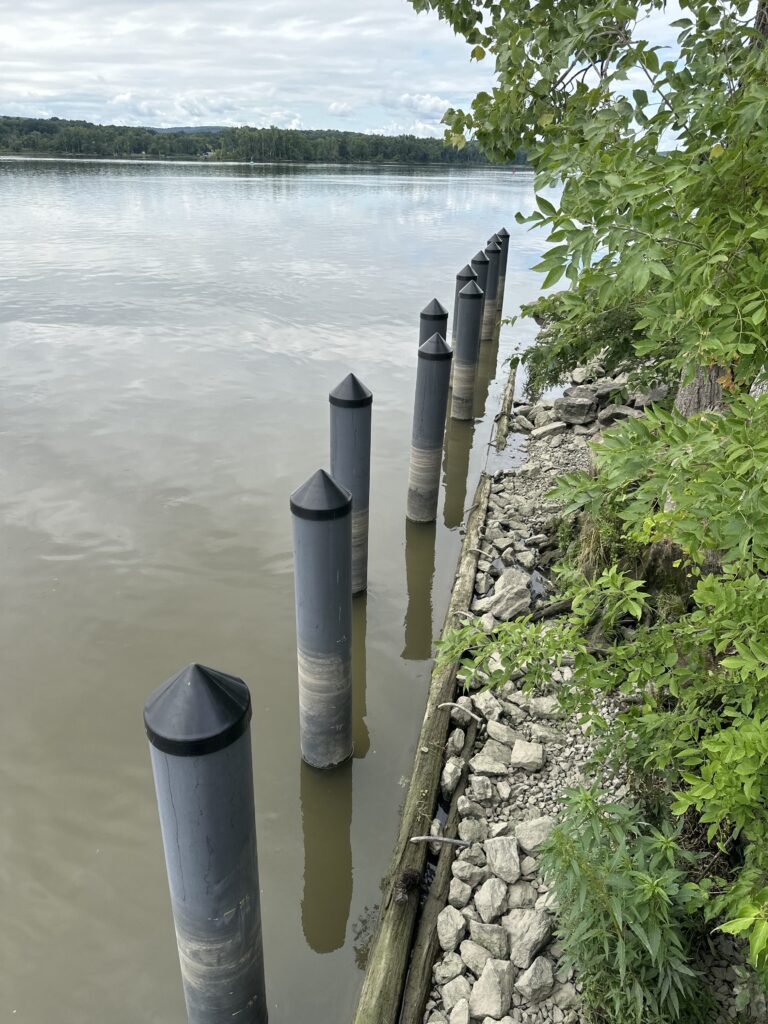 a row of pipes on a stone wall next to a body of water (MyCoast AI)