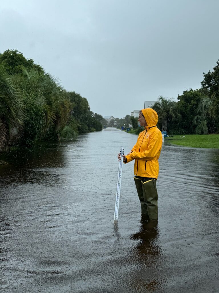 a man in a yellow jacket holding a fishing pole in a river (MyCoast AI)