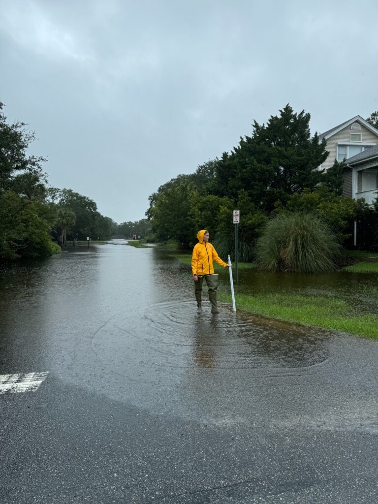 a man in a yellow rain jacket standing in a flooded street (MyCoast AI)