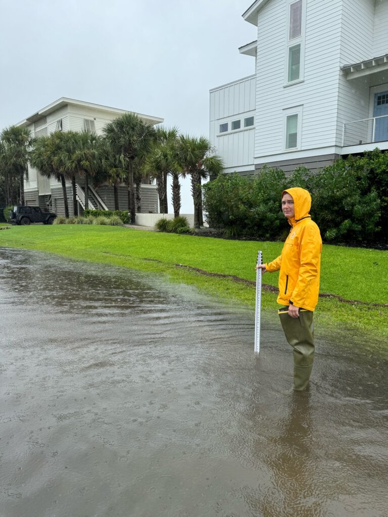 a person in a raincoat holding a stick in a puddle (MyCoast AI)