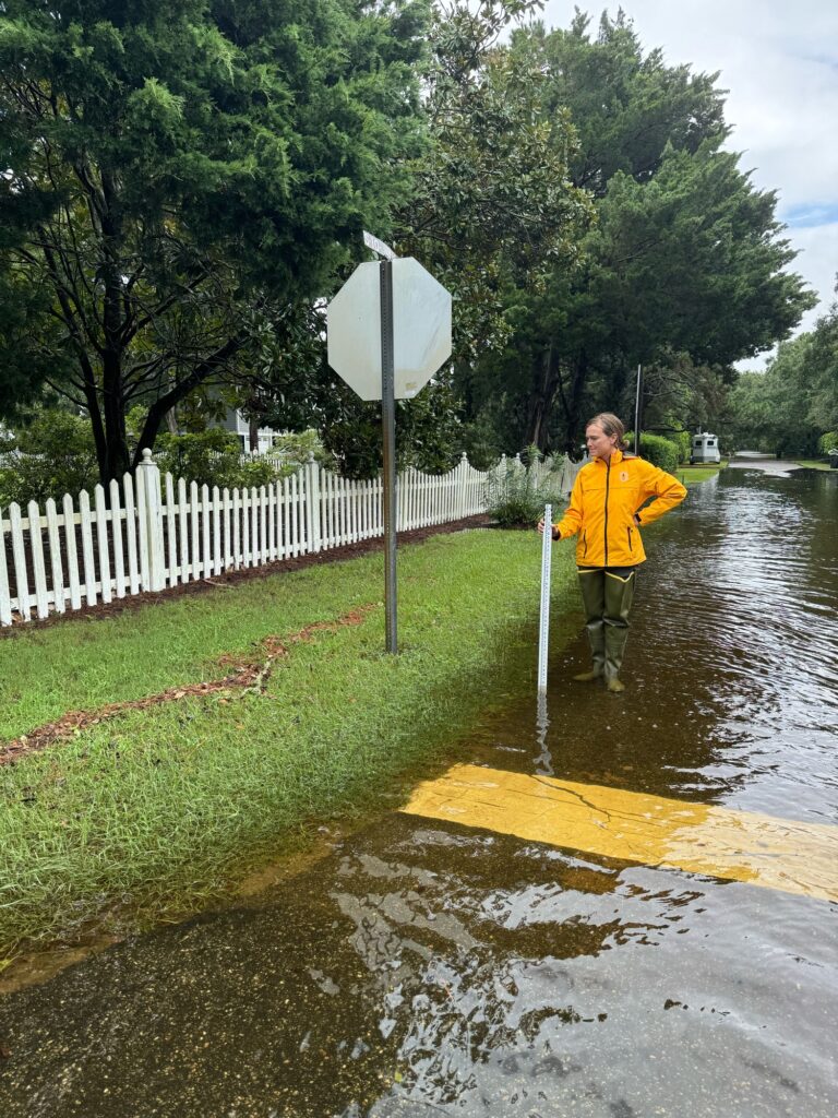 a person in a yellow jacket standing in a flooded street (MyCoast AI)