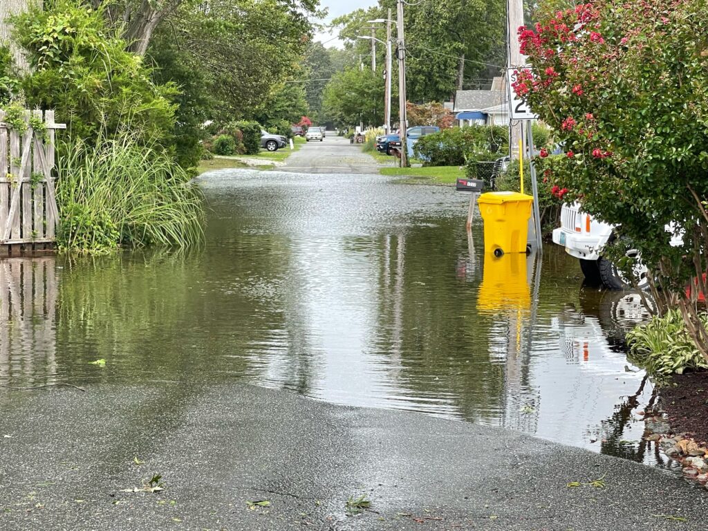 a flooded street with a yellow trash can and a white boat (MyCoast AI)