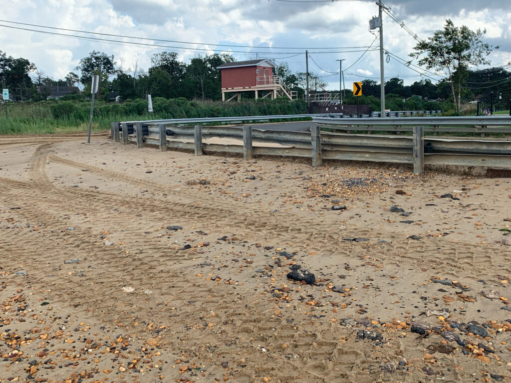 a dirt road with a fence and a building in the background (MyCoast AI)