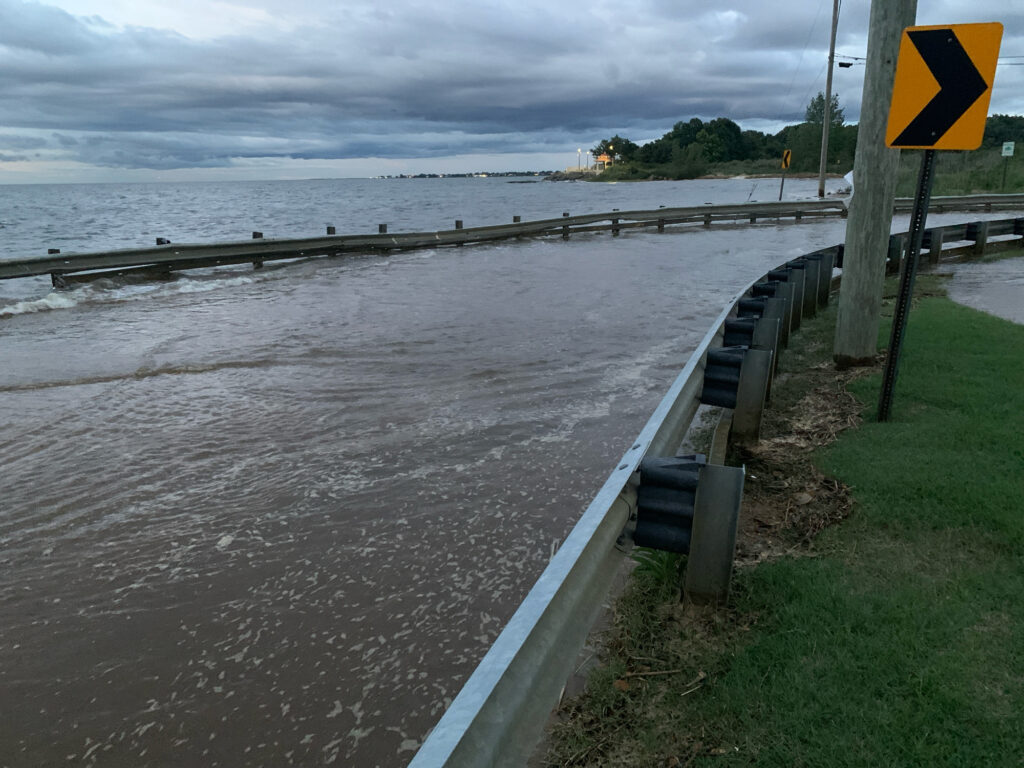 a road with a sign on it next to a body of water (MyCoast AI)