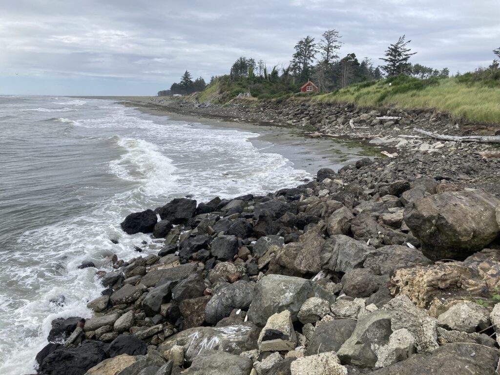 a rocky beach with a house in the background (MyCoast AI)