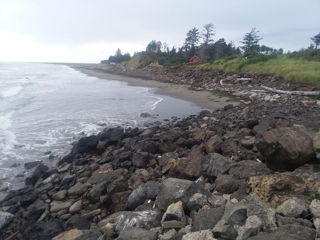 a rocky beach with a house in the distance (MyCoast AI)