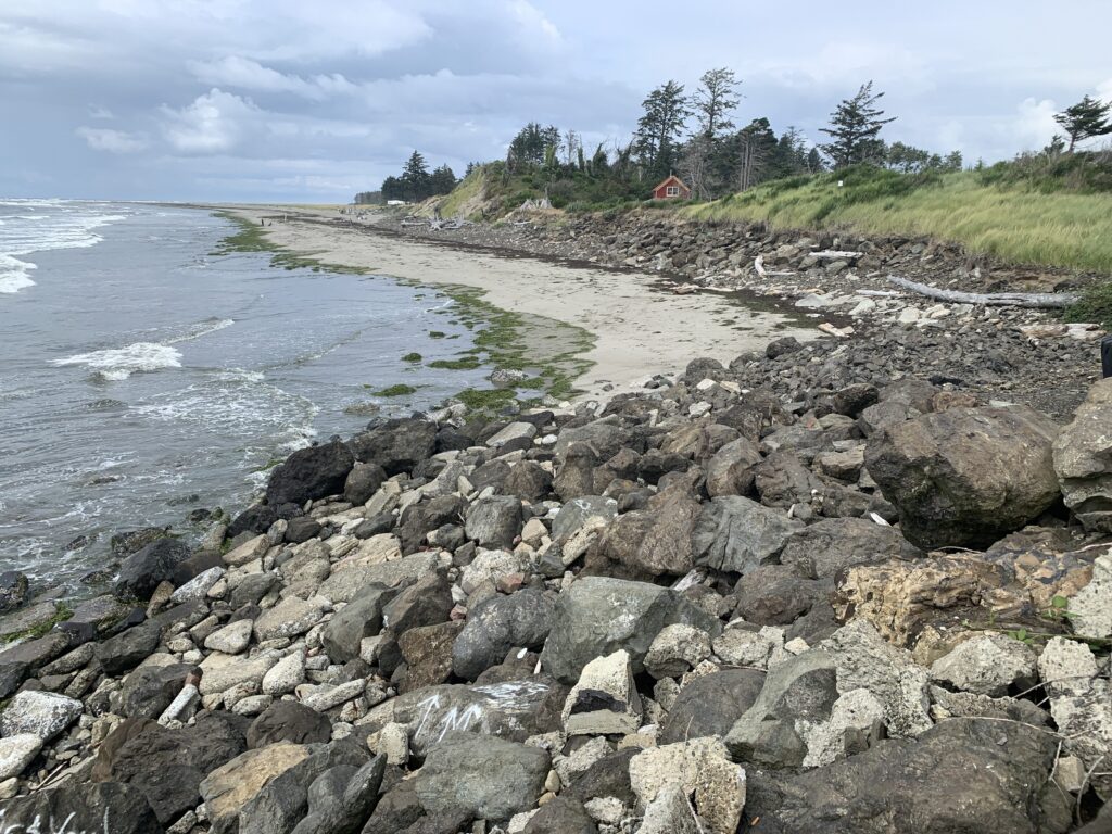a rocky beach with a house in the background (MyCoast AI)