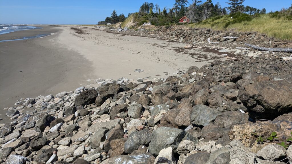 a rocky beach with a house in the background (MyCoast AI)