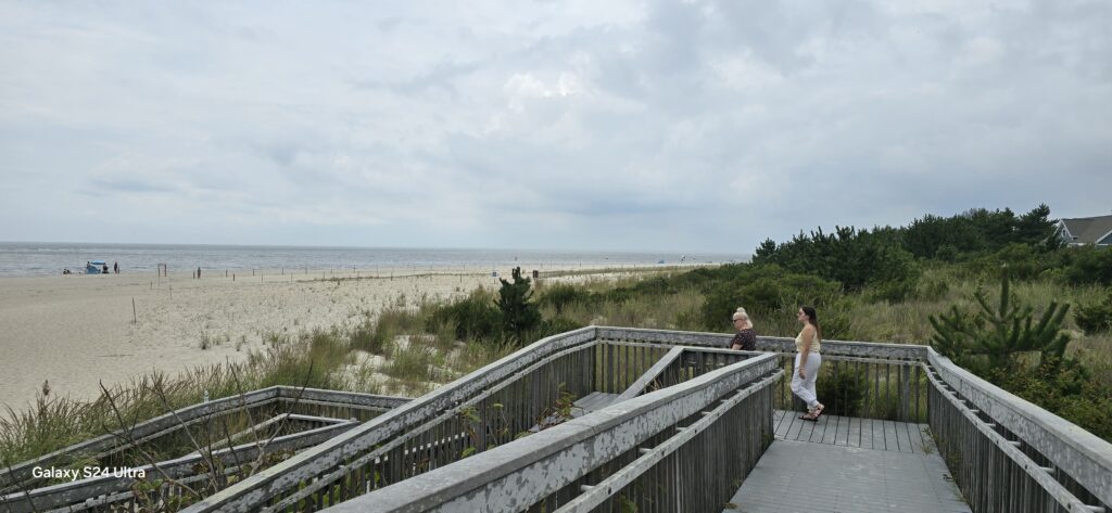a couple of people walking on a boardwalk by a beach (MyCoast AI)