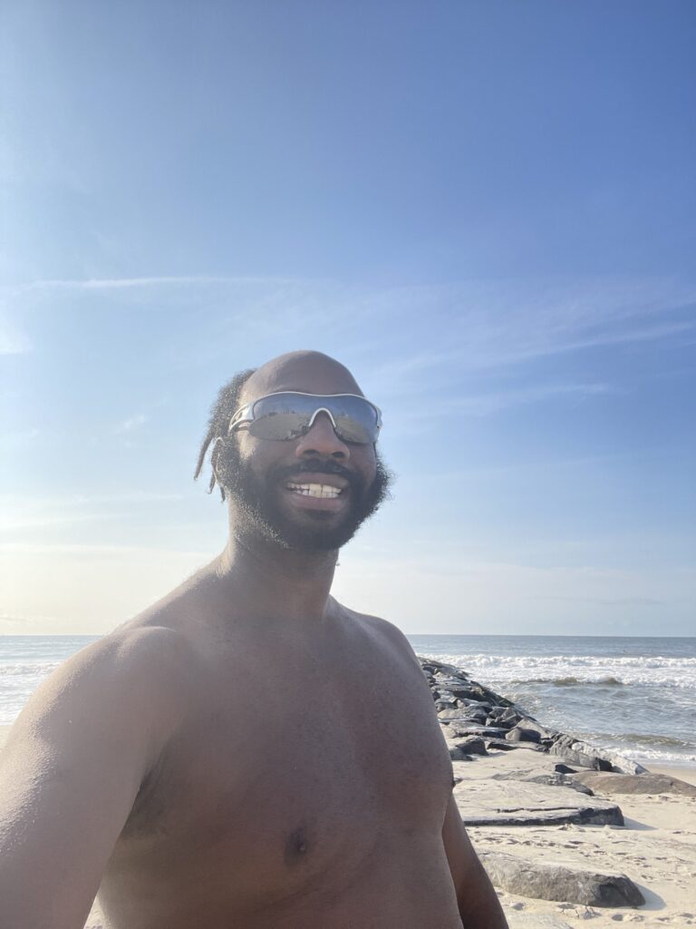 a man wearing sunglasses and standing on a beach (MyCoast AI)