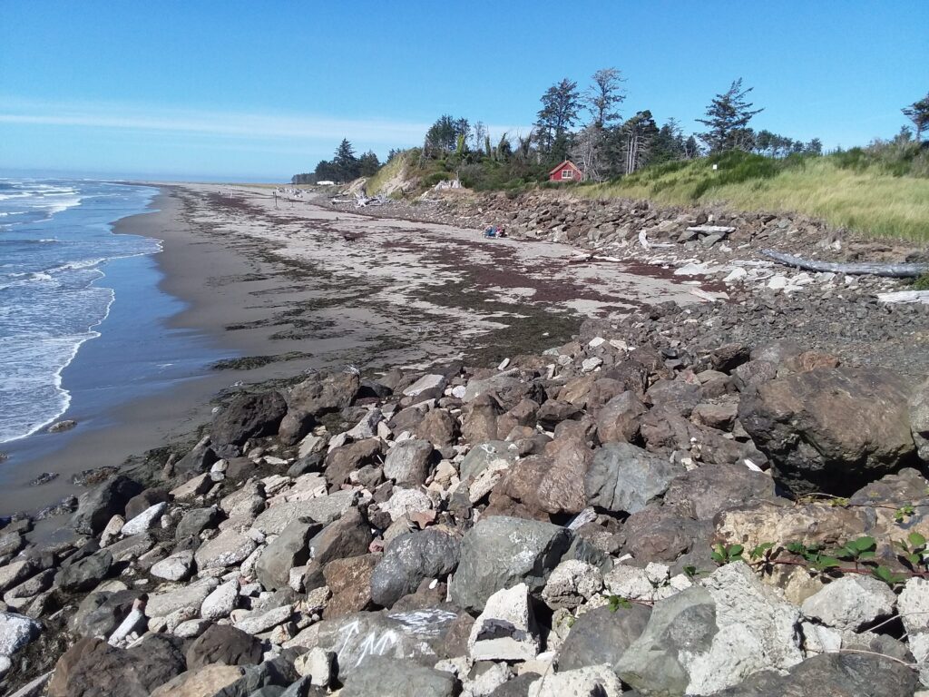 a rocky beach with a house in the background (MyCoast AI)