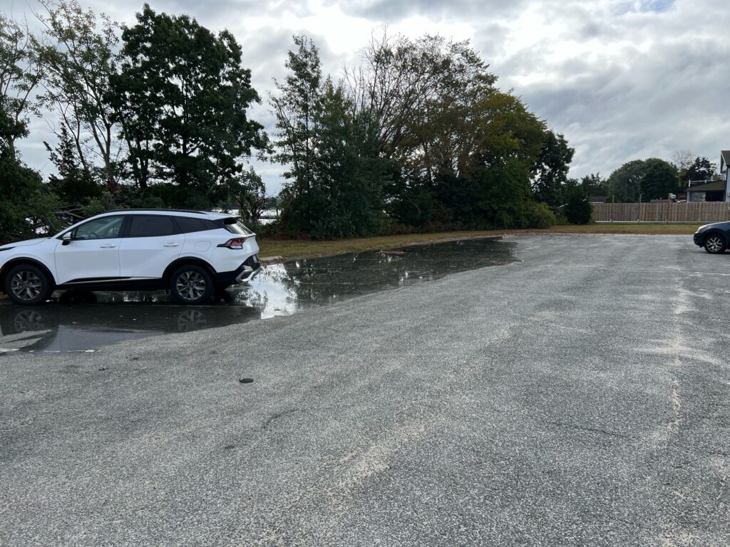 a white car parked in a parking lot with a puddle of water (MyCoast AI)