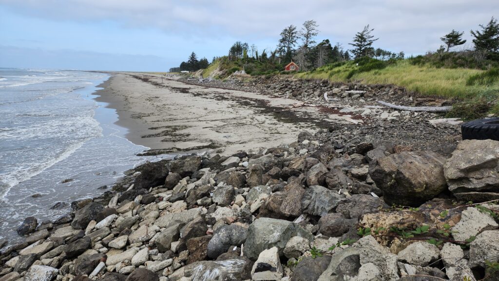 a rocky beach with a house in the background (MyCoast AI)