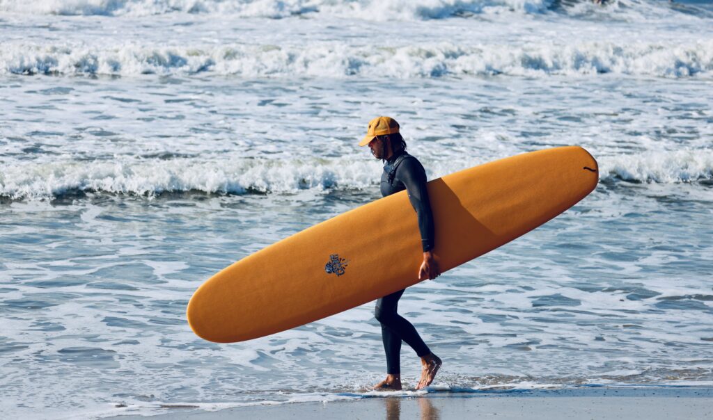 a person carrying a surfboard on the beach (MyCoast AI)