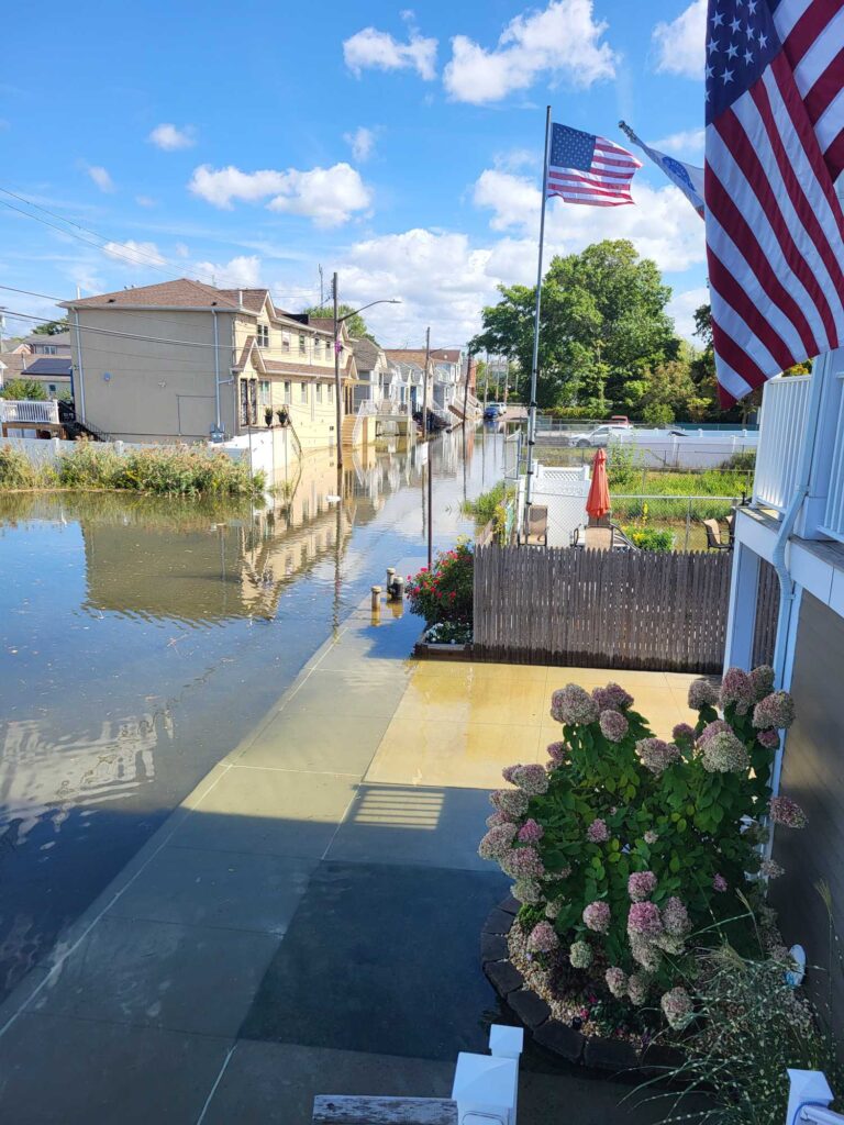 a flagpole with flowers and a flag on it by a body of water (MyCoast AI)