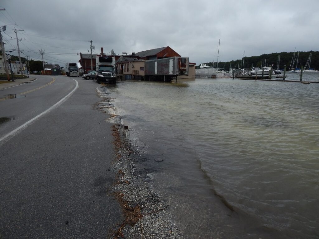 a flooded street with a building and a truck parked on the side (MyCoast AI)