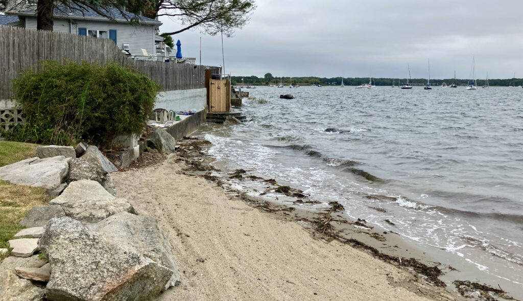 a rocky beach with a body of water and a house (MyCoast AI)
