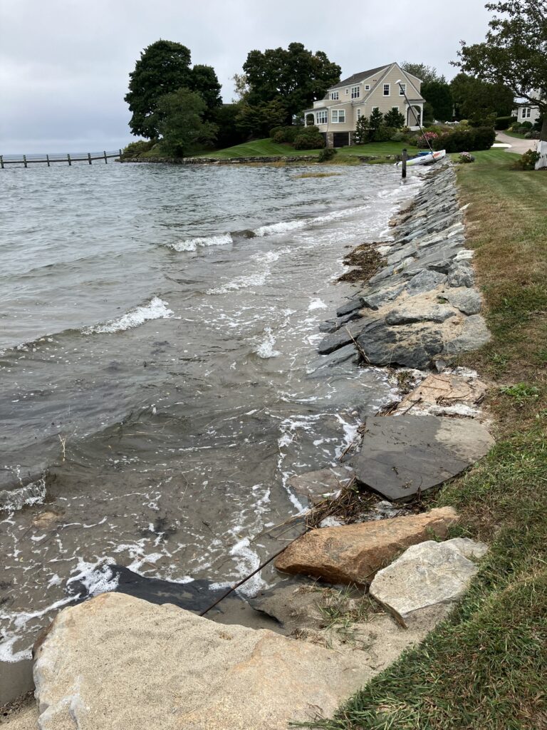 a rocky beach with a house in the background (MyCoast AI)