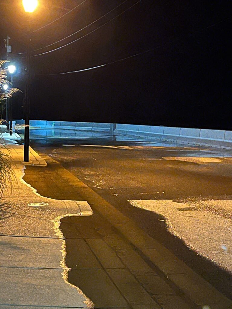 a street with a blue wall and a street light at night (MyCoast AI)