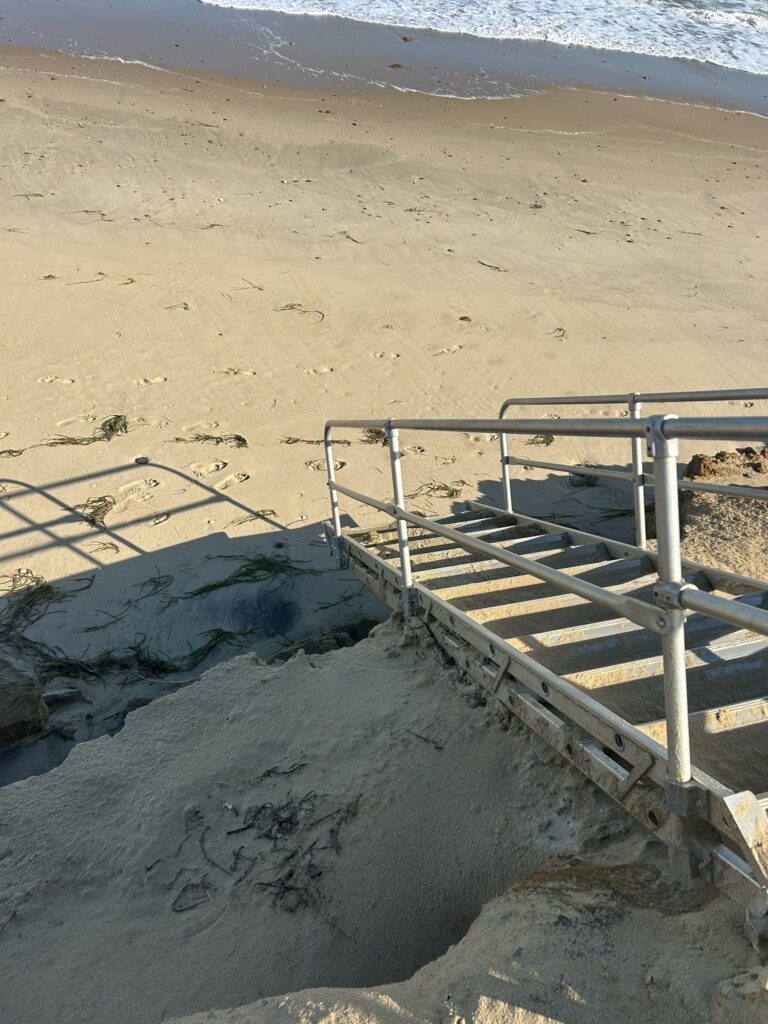 a sandy beach with a metal railing (MyCoast AI)