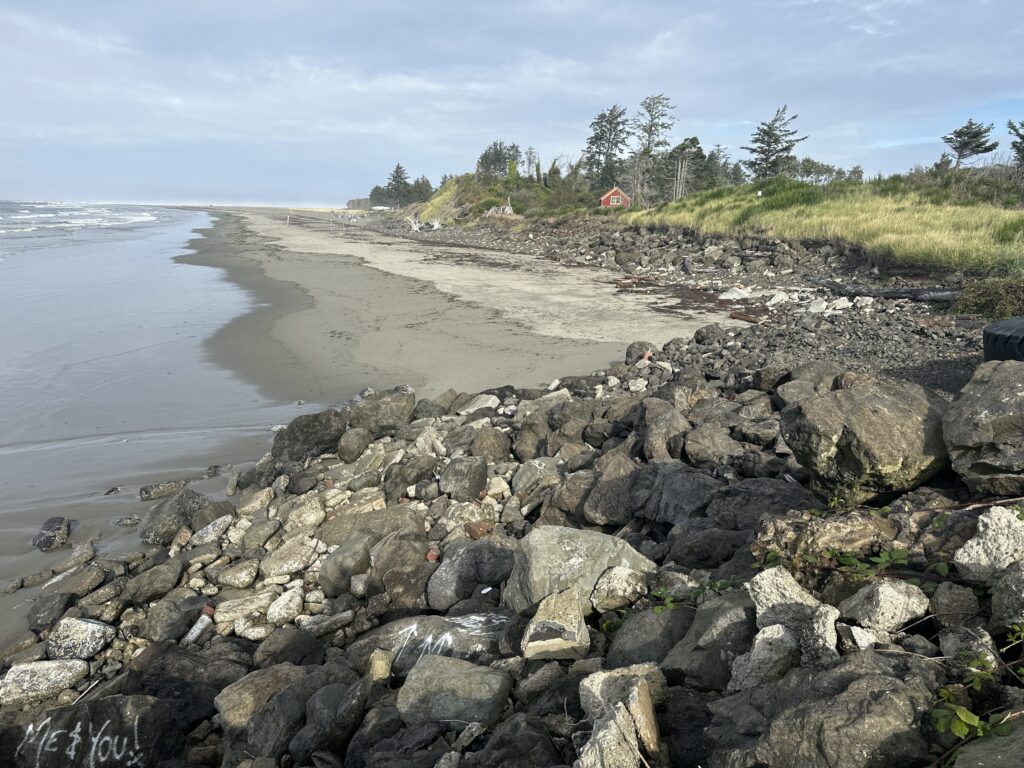 a rocky beach with a house in the background (MyCoast AI)