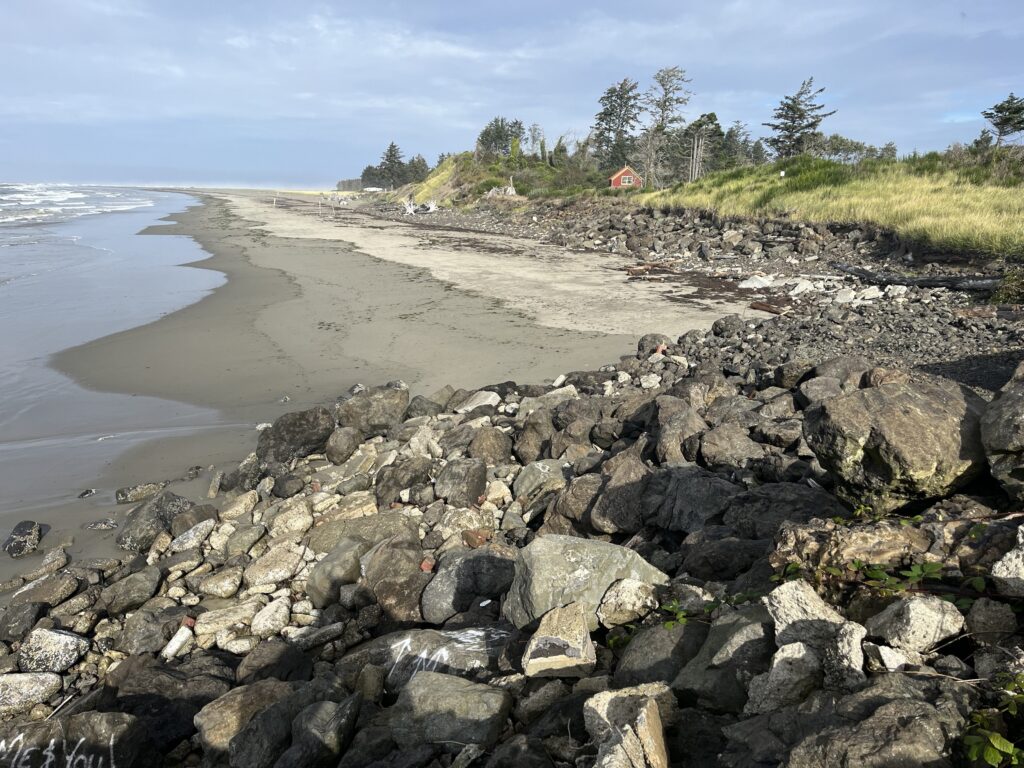 a rocky beach with a house in the background (MyCoast AI)