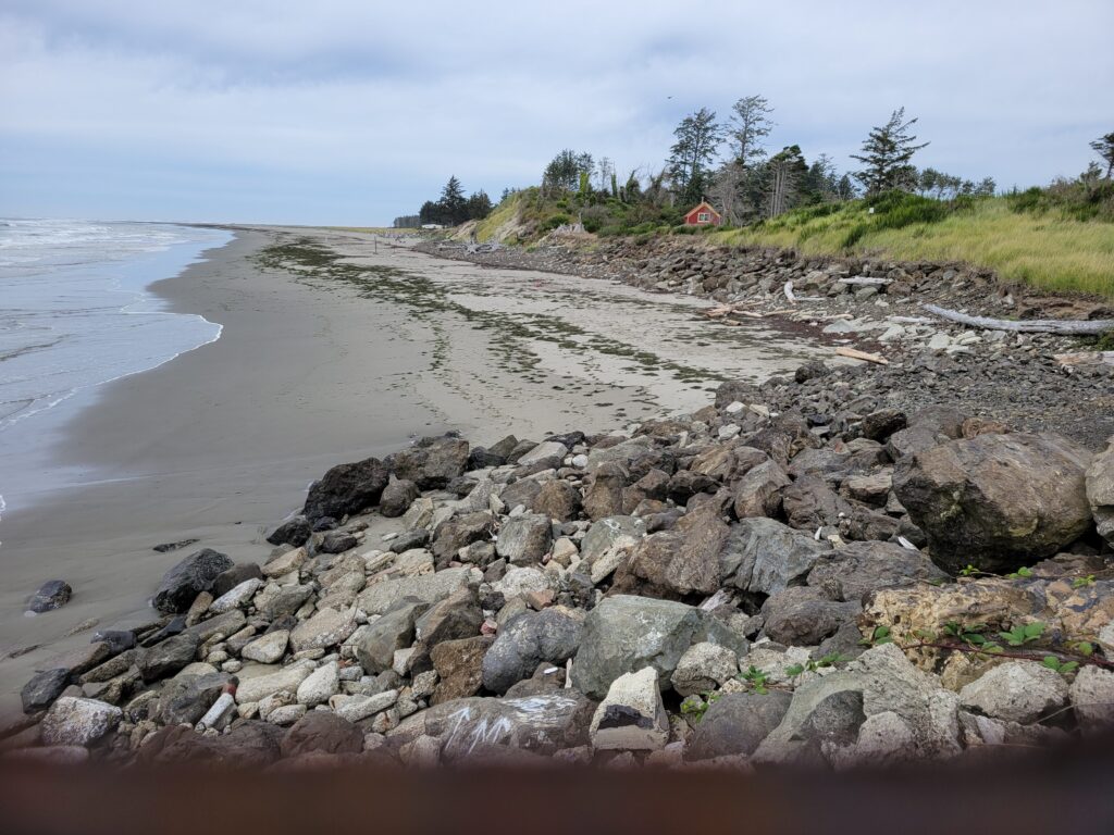 a rocky beach with a house in the background (MyCoast AI)