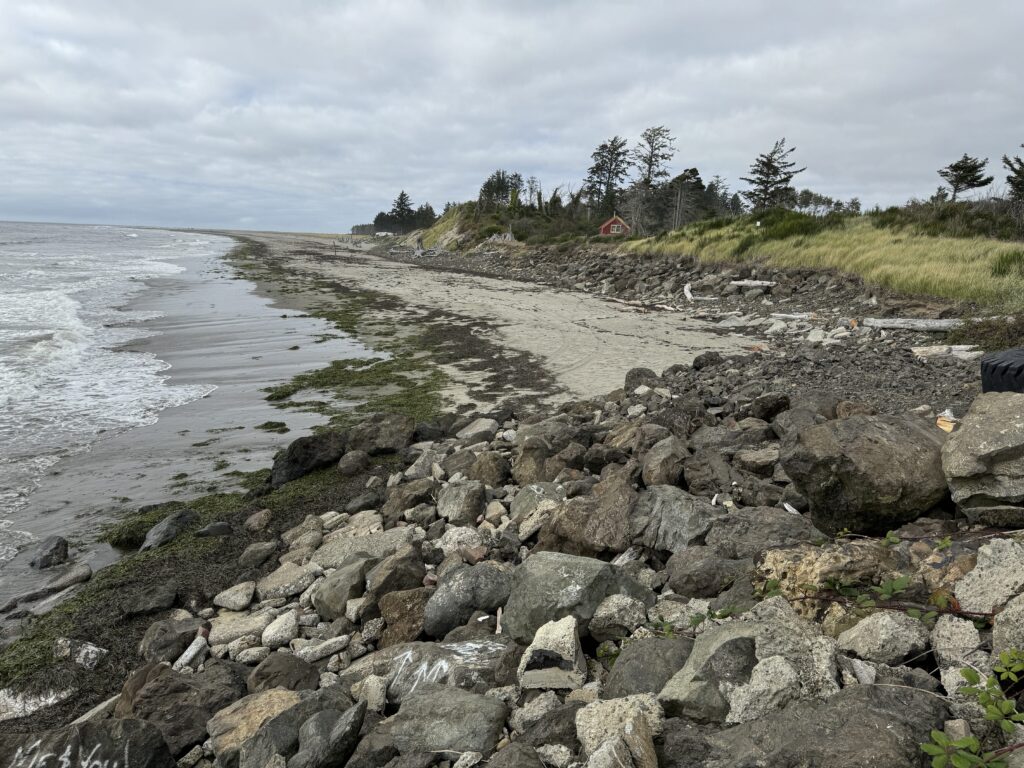 a rocky beach with a house in the distance (MyCoast AI)
