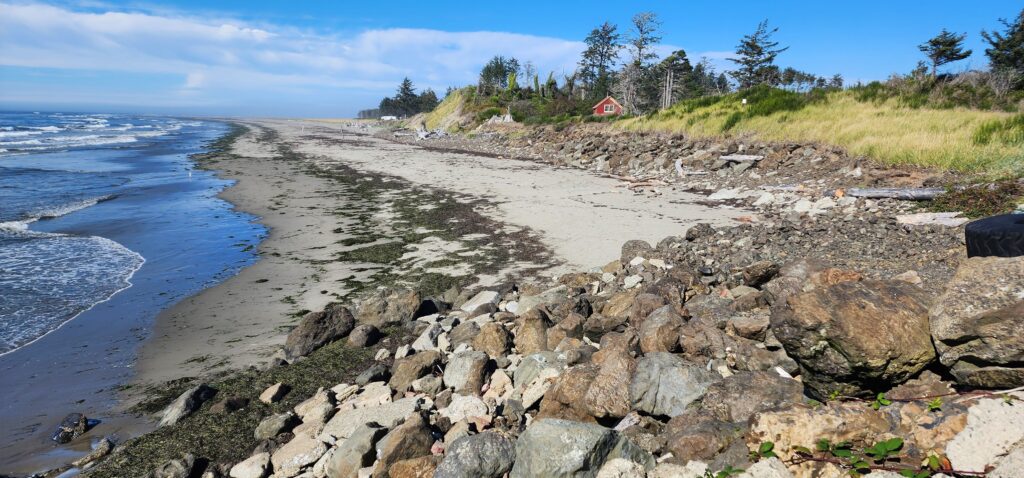 a rocky beach with a house in the distance (MyCoast AI)