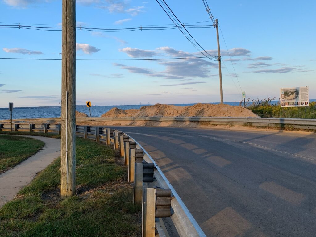 a road with a fence and a body of water in the background (MyCoast AI)