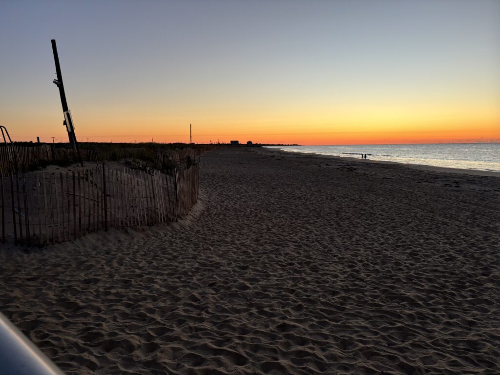 a sandy beach with a fence and a sunset (MyCoast AI)