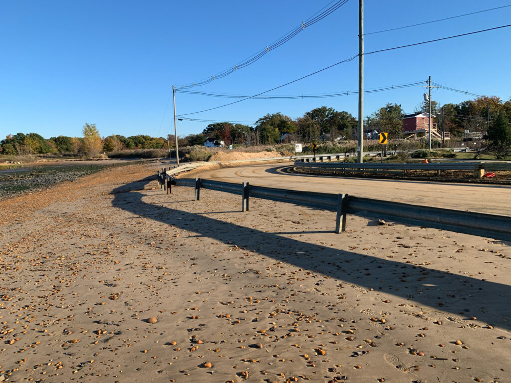 a road with a fence and a dirt road with power lines (MyCoast AI)