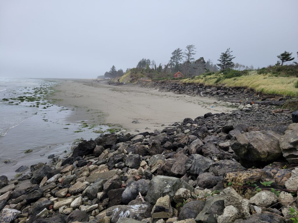 a rocky beach with a house in the distance (MyCoast AI)
